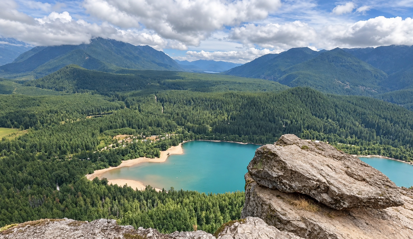 Rattlesnake Lake and forested mountains seen from the rocky ledge