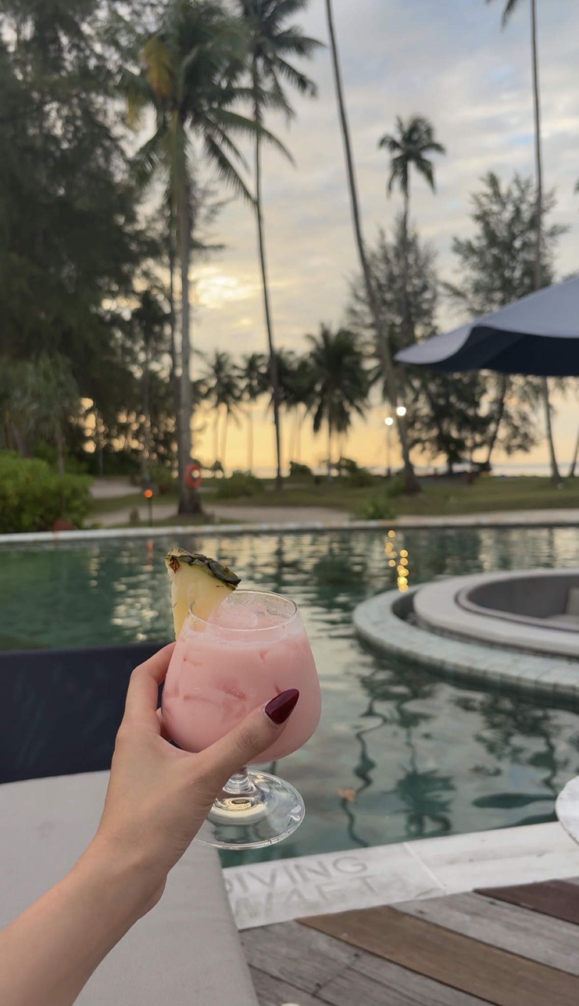 Pink drink by the pool at sunset